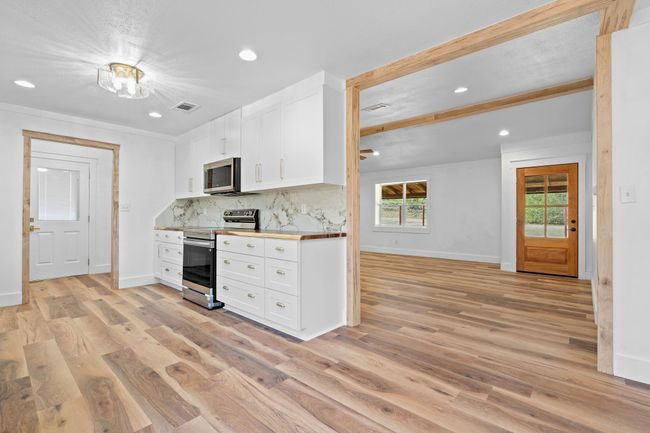 Kitchen featuring light wood finished floors, white cabinetry, visible vents, and stainless steel appliances | Image 21
