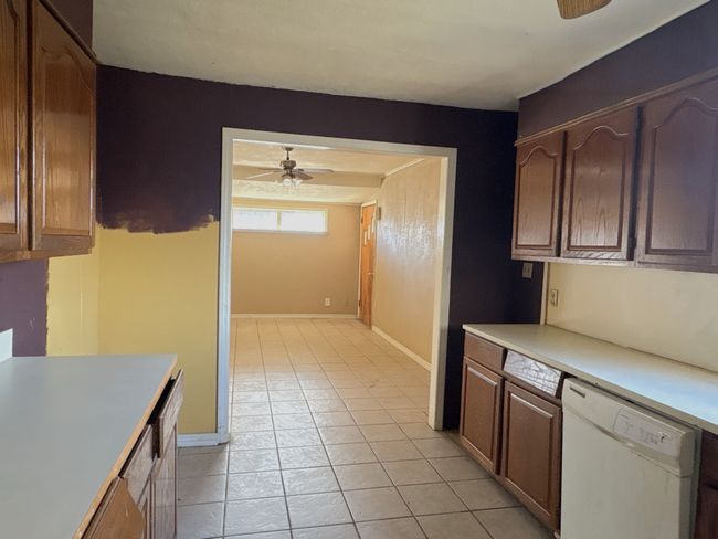 Kitchen with light tile patterned floors, baseboards, white dishwasher, ceiling fan, and light countertops | Image 5