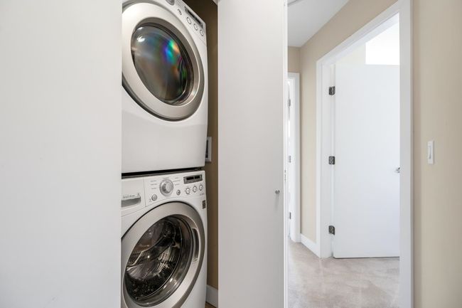 Laundry area featuring stacked washer and clothes dryer, laundry area, light colored carpet, and baseboards | Image 17