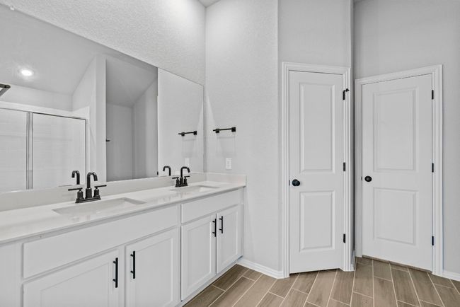 Bathroom featuring a shower stall, double vanity, a sink, and wood tiled floor | Image 17