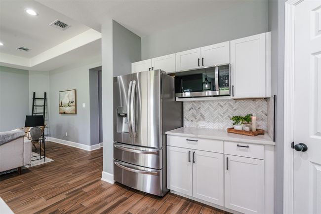 Kitchen with stainless steel appliances, decorative backsplash, dark wood-style floors, light countertops, and recessed lighting | Image 10