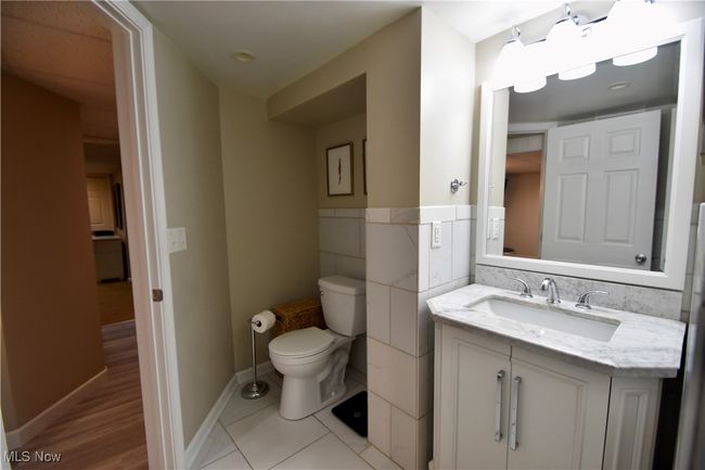 Half bathroom featuring toilet, vanity, tile walls, a wainscoted wall, and tile patterned floors | Image 23