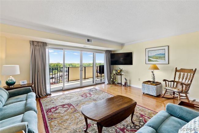 Living room with a textured ceiling, wood finished floors, and visible vents | Image 4