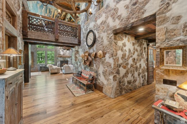Living area with wood-type flooring, beamed ceiling, a lit fireplace, and a chandelier | Image 12
