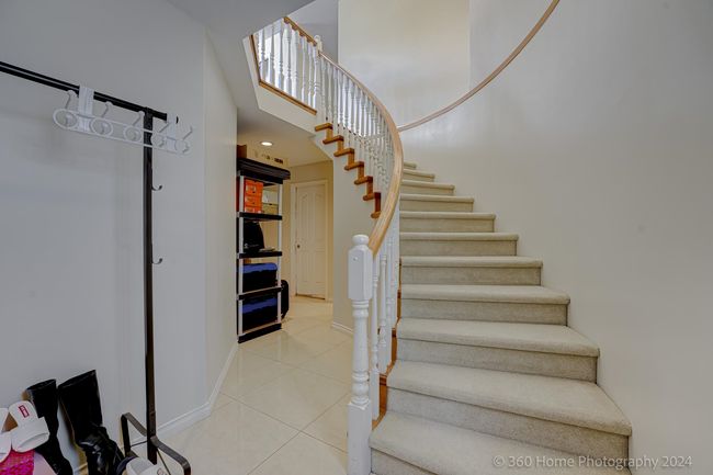 Staircase with baseboards, a high ceiling, and tile patterned flooring | Image 13