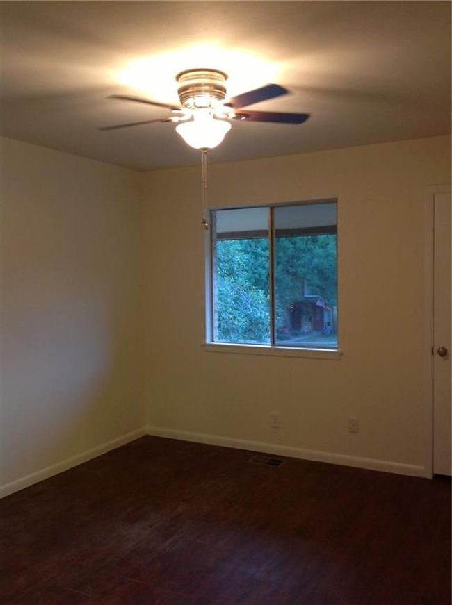 Spare room with a ceiling fan, baseboards, and dark wood-type flooring | Image 6