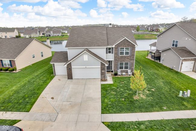 traditional-style house with brick siding, a shingled roof, a water view, a residential view, and an attached garage | Image 46
