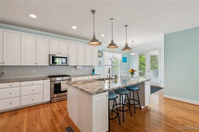 Granite countertops, timeless white kitchen cabinetry with crown, gas cooking and stainless steel appliances. Kitchen island has an Insinkerator Hot Water Dispenser for instant hot water. | Image 7