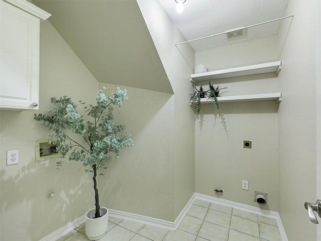 Laundry room with hookup for an electric dryer, hookup for a gas dryer, hookup for a washing machine, light tile patterned flooring, and cabinet space | Image 31
