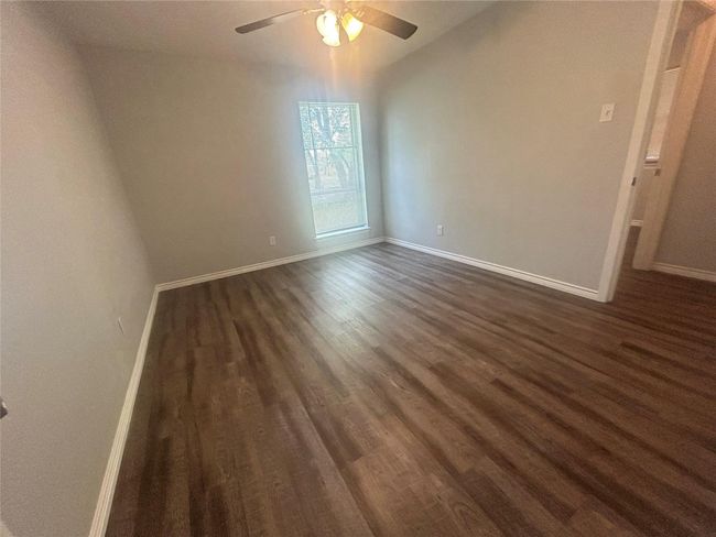 Unfurnished room with dark wood finished floors, a ceiling fan, and baseboards | Image 11