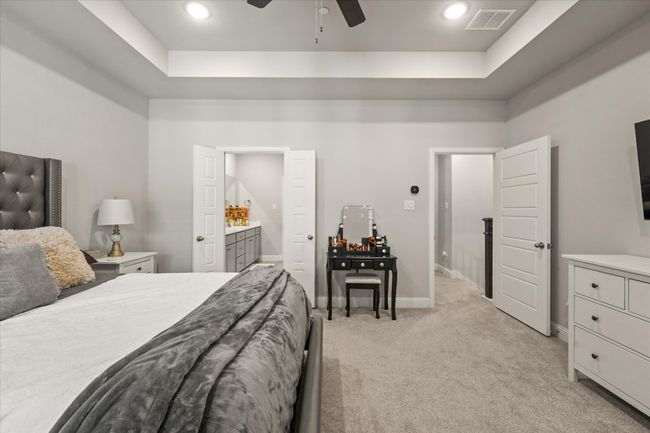 Bedroom featuring a raised ceiling, light carpet, recessed lighting, ceiling fan, and ensuite bathroom | Image 24
