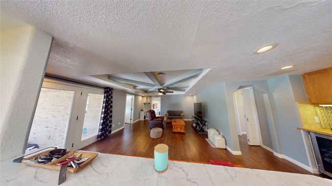 Living room with dark wood finished floors, beverage cooler, a ceiling fan, a textured ceiling, and recessed lighting | Image 8