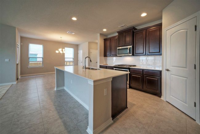 Kitchen with a sink, visible vents, appliances with stainless steel finishes, and a chandelier | Image 10