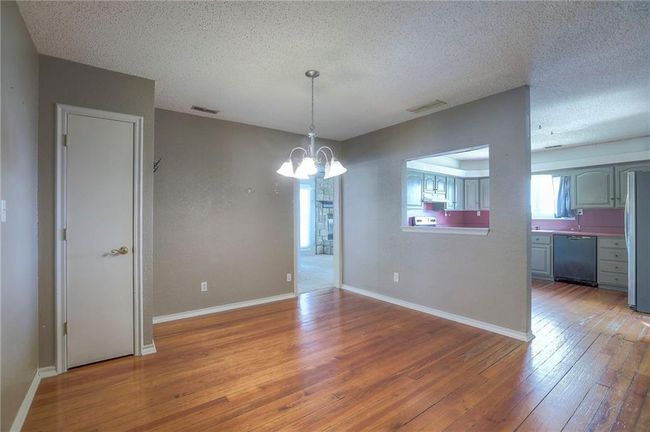 Unfurnished dining area with baseboards, a textured ceiling, light wood-style flooring, and a notable chandelier | Image 27