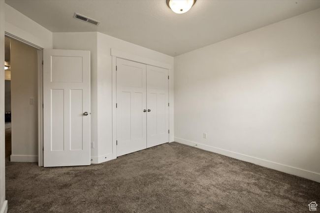 Unfurnished bedroom featuring a closet, dark carpet, visible vents, and baseboards | Image 21