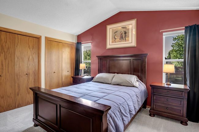Bedroom with light colored carpet, lofted ceiling, and two closets | Image 18