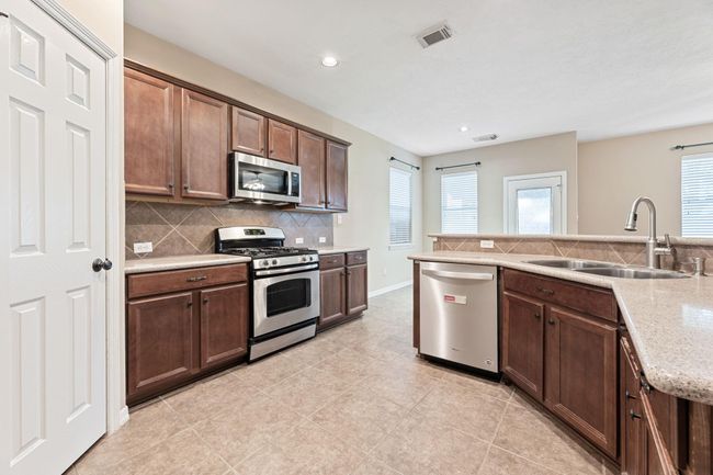 Open kitchen area with stainless appliances allows for easy flow of traffic, perfect for those busy mornings! | Image 16