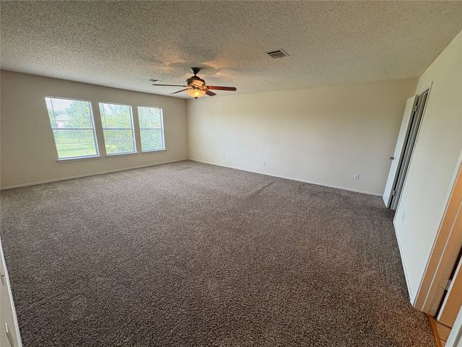Carpeted empty room featuring a textured ceiling and ceiling fan | Image 11