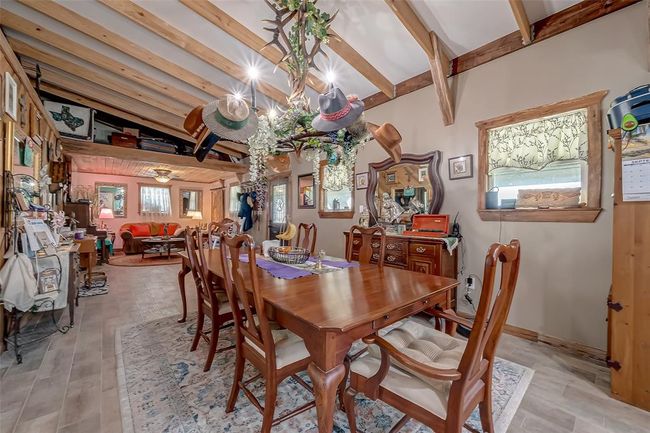 Situated between the kitchen and living area, the dining space is both functional and atmospheric. A statement chandelier adds flair, while windows and a paneled accent wall provide balance and warmth. | Image 7