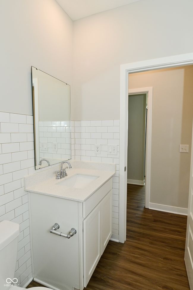 half bathroom featuring vanity, a wainscoted wall, toilet, tile walls, and wood finished floors | Image 24