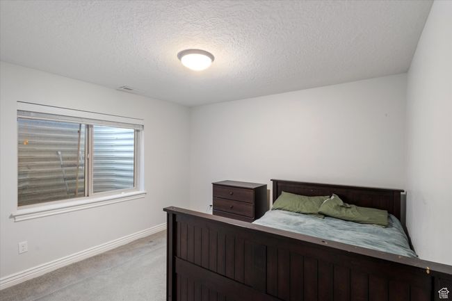 Bedroom featuring light colored carpet, a textured ceiling, and baseboards | Image 17