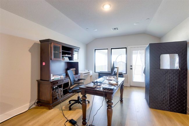 Home office with light wood-type flooring, baseboards, vaulted ceiling, and visible vents | Image 17
