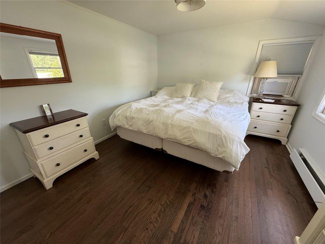 Bedroom with refinished wood floors, a baseboard radiator, lofted ceiling | Image 21