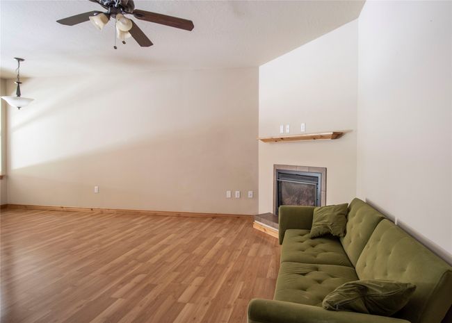Living area with light wood-style floors, a fireplace with raised hearth, and a ceiling fan | Image 9