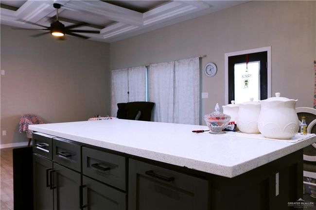 Kitchen with coffered ceiling, baseboards, a kitchen island, beamed ceiling, and ceiling fan | Image 11