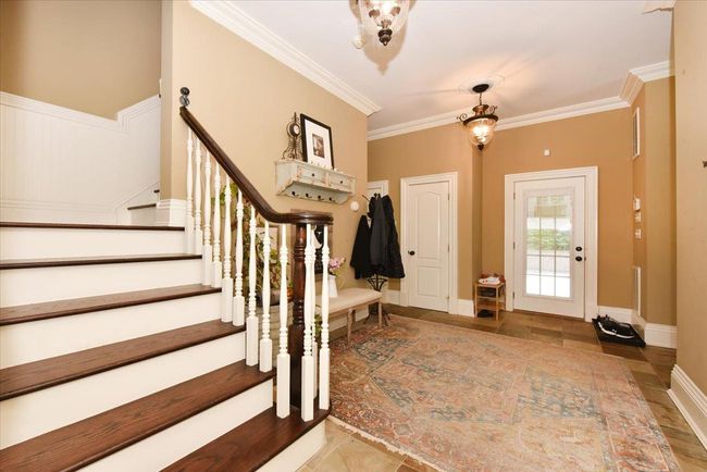 Living area with healthy amount of natural light, wood finished floors, crown molding, a high end fireplace, and recessed lighting | Image 10