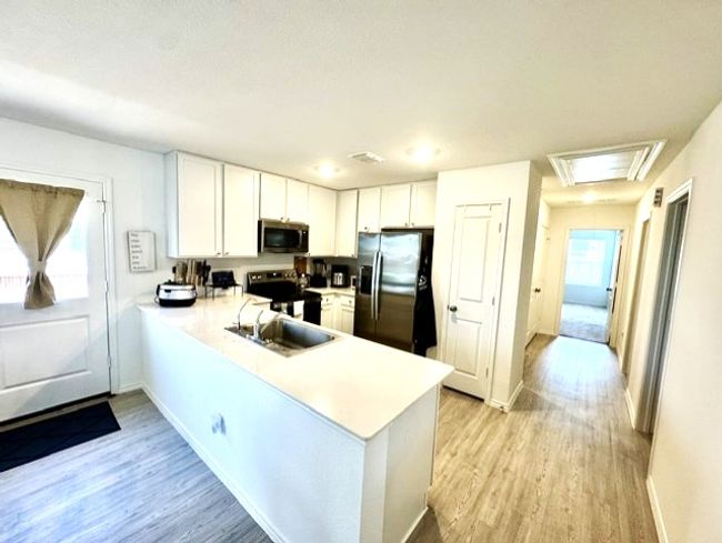 Kitchen featuring stainless steel appliances, light countertops, light wood-style floors, and a peninsula | Image 10