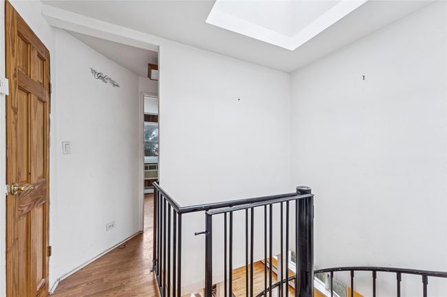 Hallway featuring an upstairs landing, a skylight, and wood finished floors | Image 7