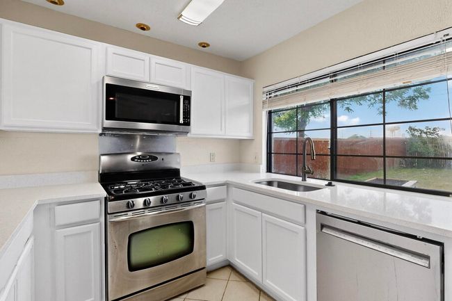 Kitchen featuring appliances with stainless steel finishes, light countertops, white cabinets, and light tile patterned floors | Image 14