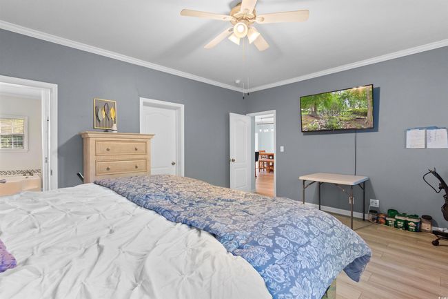 Bedroom featuring light wood-style flooring, ornamental molding, ceiling fan, and connected bathroom | Image 12