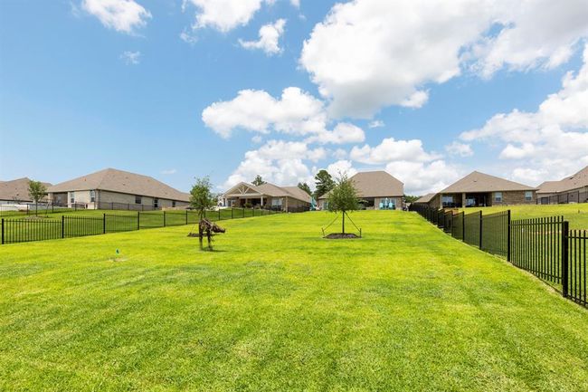Spacious backyard with well-maintained lawn, trees, and surrounded by a black metal fence. | Image 43