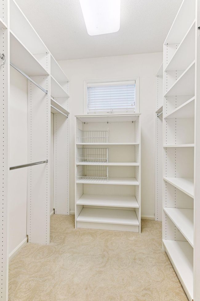 CustomSpacious walk-in closet featuring custom built-in shelving, hanging rods, and organized storage solutions for the ultimate in wardrobe organization and luxury dressing room experience. | Image 44