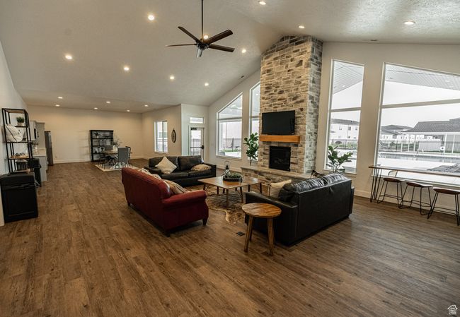Living room featuring a ceiling fan, a fireplace, dark wood-type flooring, high vaulted ceiling, and recessed lighting | Image 15