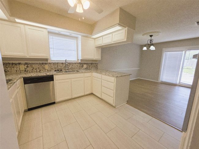 Unfurnished dining area with wood finished floors, a sink, a chandelier, a textured ceiling, and baseboards | Image 13