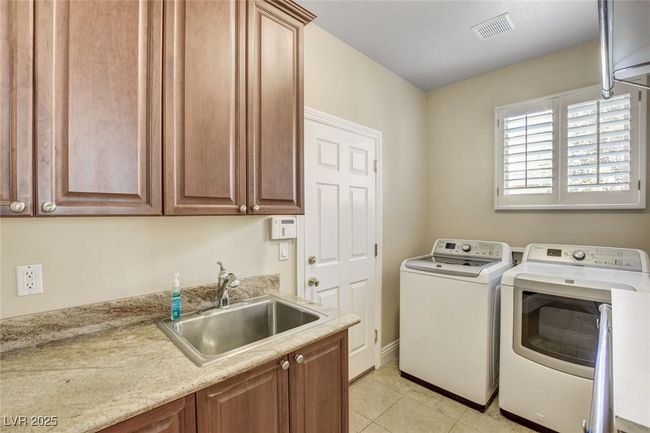 Laundry room featuring light tile patterned floors, independent washer and dryer, a sink, visible vents, and cabinet space | Image 20
