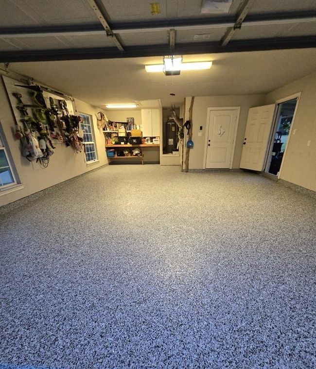 This spacious garage features a polished speckled floor and ample storage with wall-mounted racks and shelves. It also includes a window for natural light and multiple access doors. Ideal for organization and utility. | Image 38