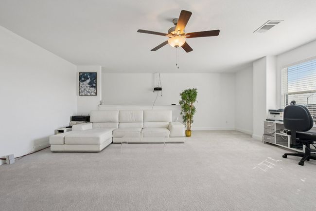 Carpeted living area with a desk and a ceiling fan | Image 26