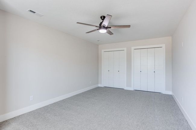 Unfurnished bedroom featuring multiple closets, carpet floors, baseboards, and a ceiling fan | Image 13