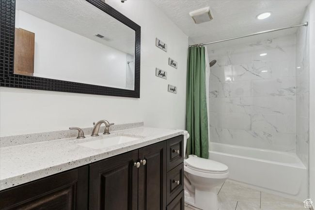Bathroom featuring shower / bathtub combination with curtain, vanity, tile patterned floors, and a textured ceiling | Image 20