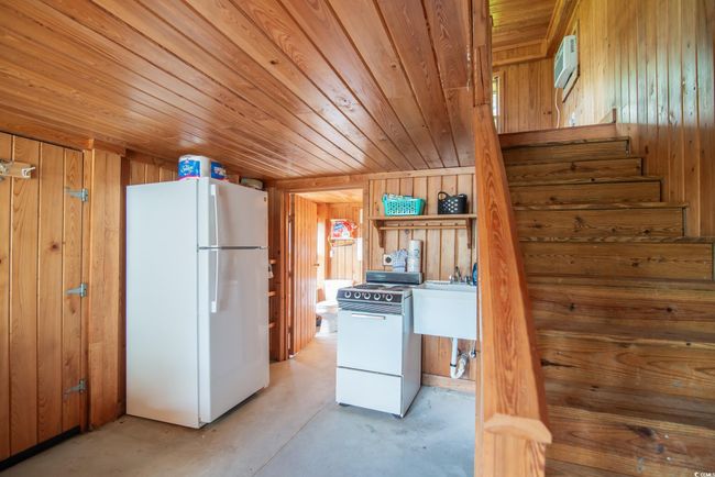 Kitchen featuring white appliances, wooden walls, concrete floors, and wooden ceiling | Image 9