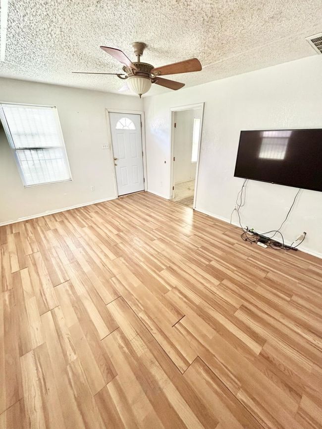 Unfurnished living room with light wood finished floors, a ceiling fan, a textured ceiling, and baseboards | Image 11