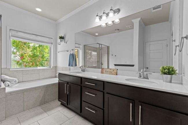 Bathroom featuring tile patterned floors, double vanity, a shower stall, a bath, and ornamental molding | Image 28