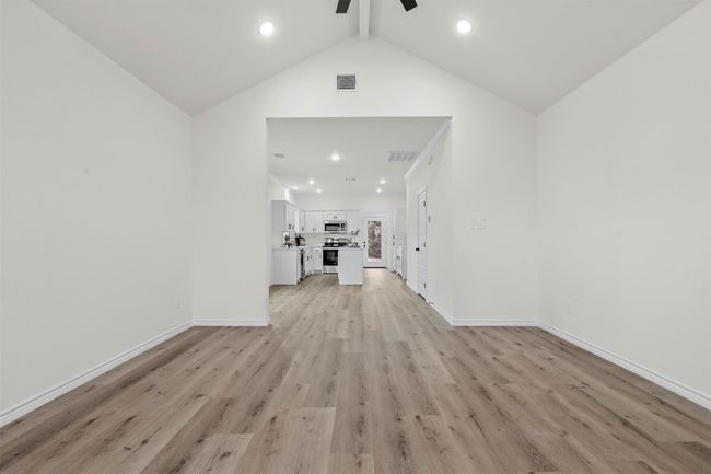 Unfurnished living room featuring light hardwood / wood-style floors, ceiling fan, and lofted ceiling with beams | Image 5