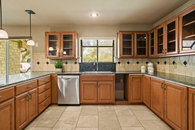 Kitchen featuring dishwasher, plenty of natural light, brown cabinets, dark stone counters, and recessed lighting | Image 7
