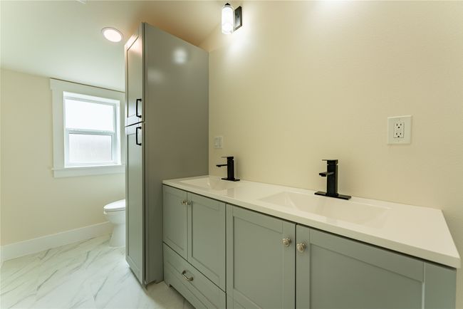 Bathroom with toilet, marble finish floor, baseboards, and a sink | Image 17