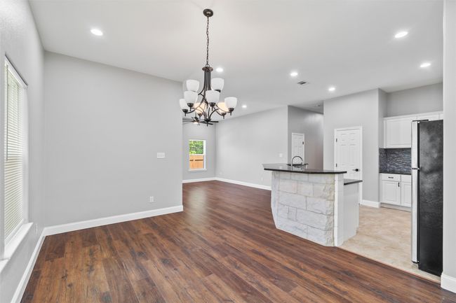 Kitchen featuring fridge, pendant lighting, backsplash, and white cabinets | Image 5